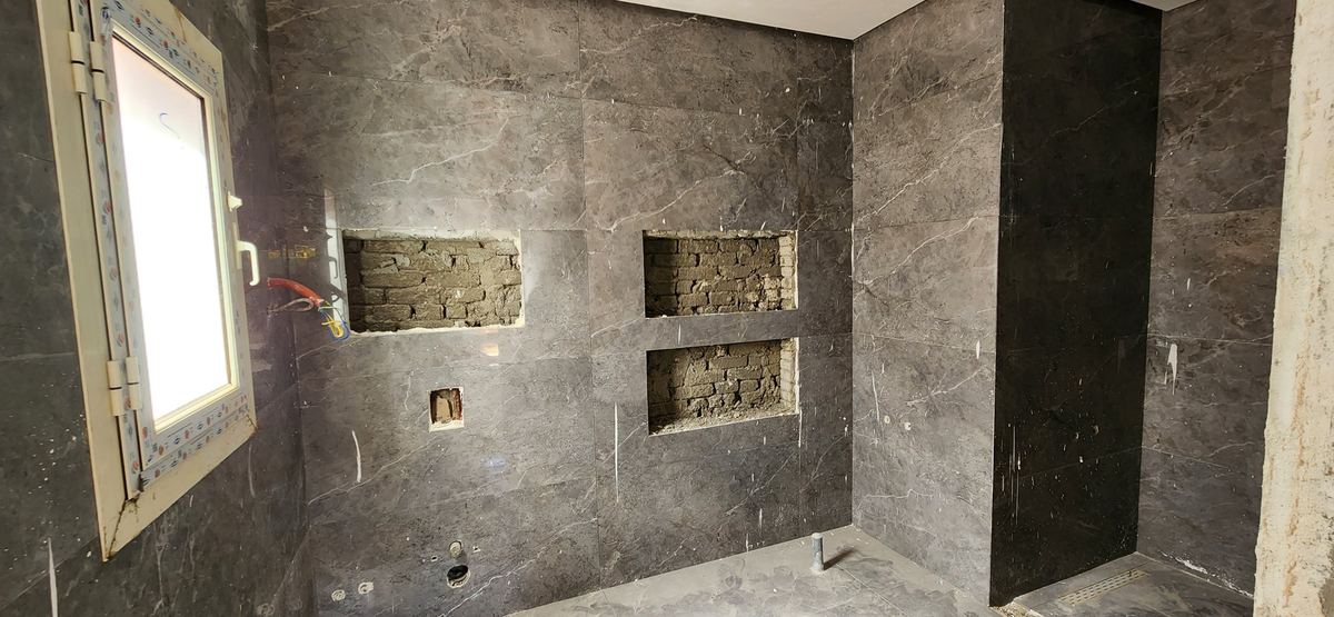 During: L-Villa bathroom during works: niches formed in the stone-look tiled wall