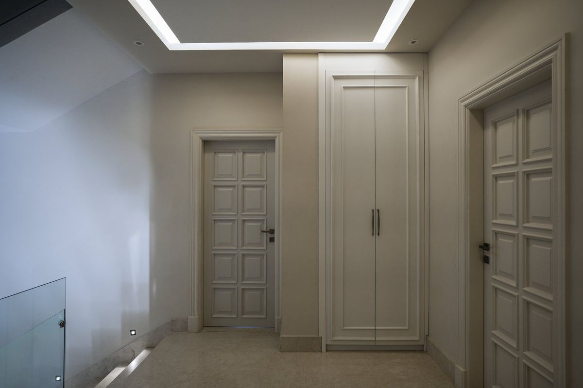 L-Villa upper hallway: panelled doors, a built-in cupboard and a lit ceiling cove