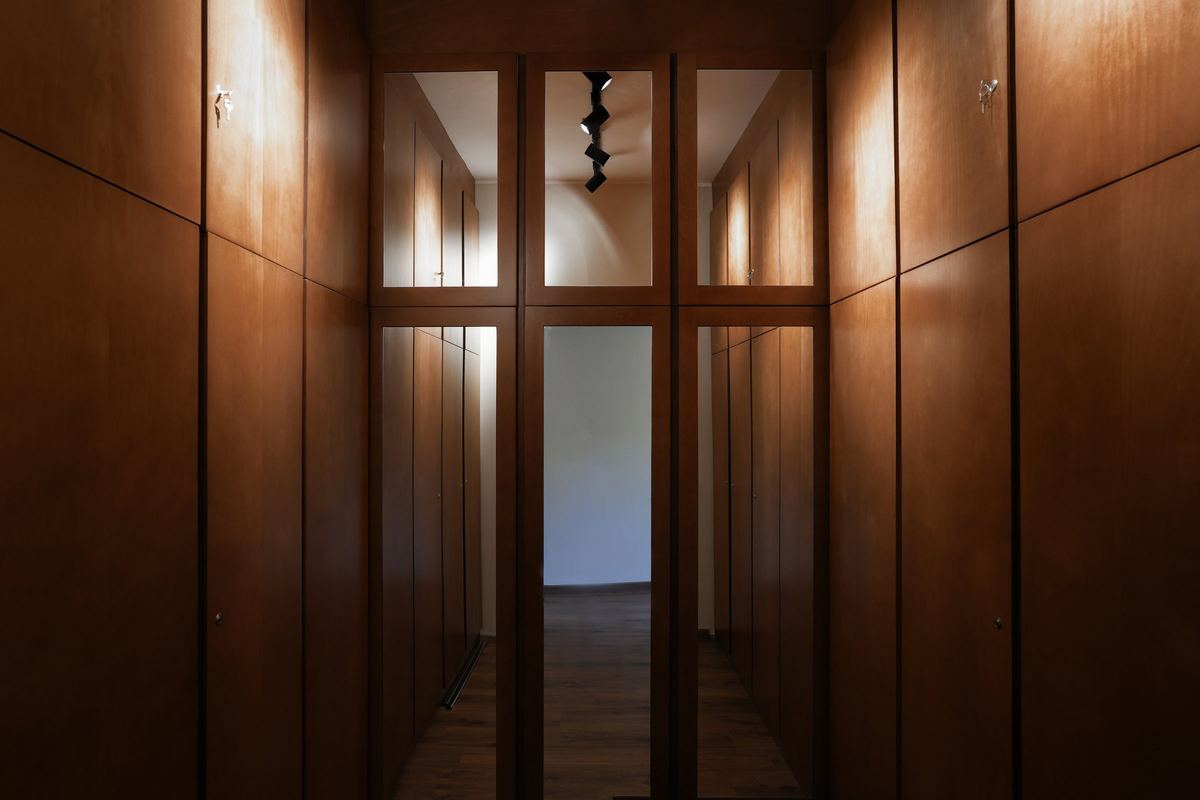 L-Villa walk-in dressing room: floor-to-ceiling dark timber wardrobes