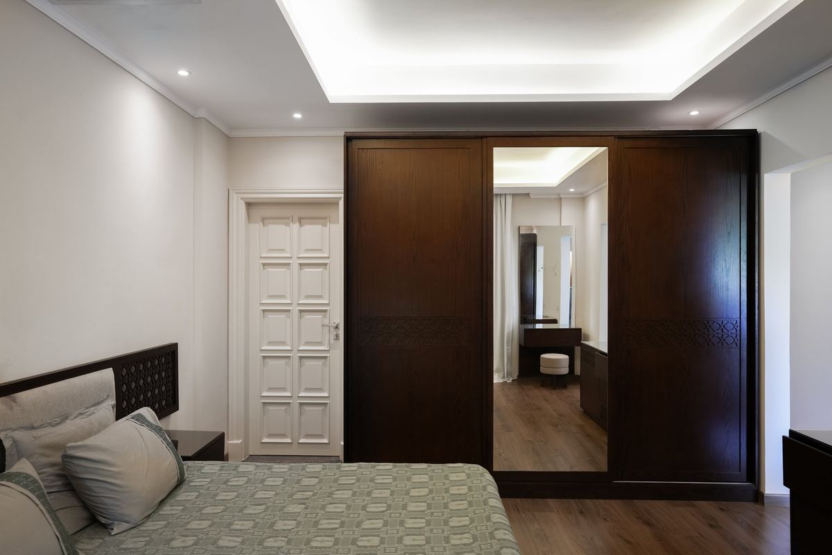 L-Villa master bedroom: dark timber wardrobe with a mirror door and a cove-lit ceiling
