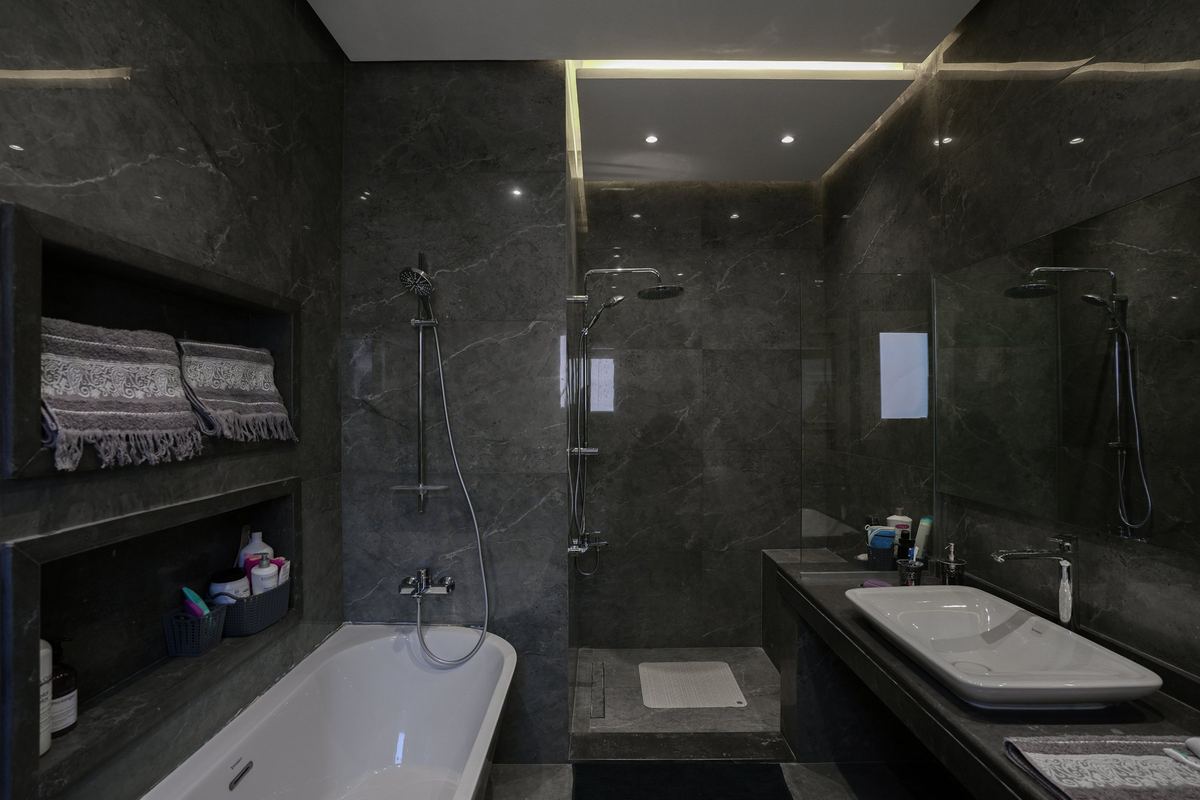 The bathroom as delivered: grey stone, lit niches, bathtub, walk-in shower and vanity
