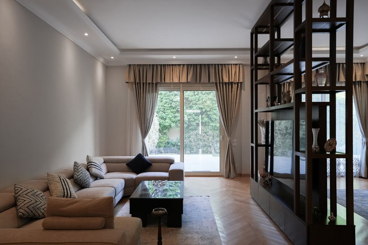 The living room as delivered: corner sofa, curtained garden doors and the shelving divider