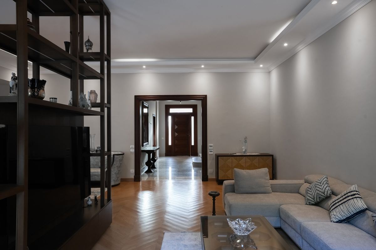 L-Villa living room with herringbone parquet, timber shelving and a view through to the front door