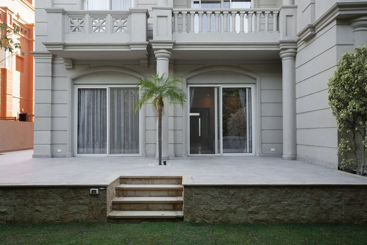 L-Villa garden façade: stone-clad terrace, steps and a palm tree