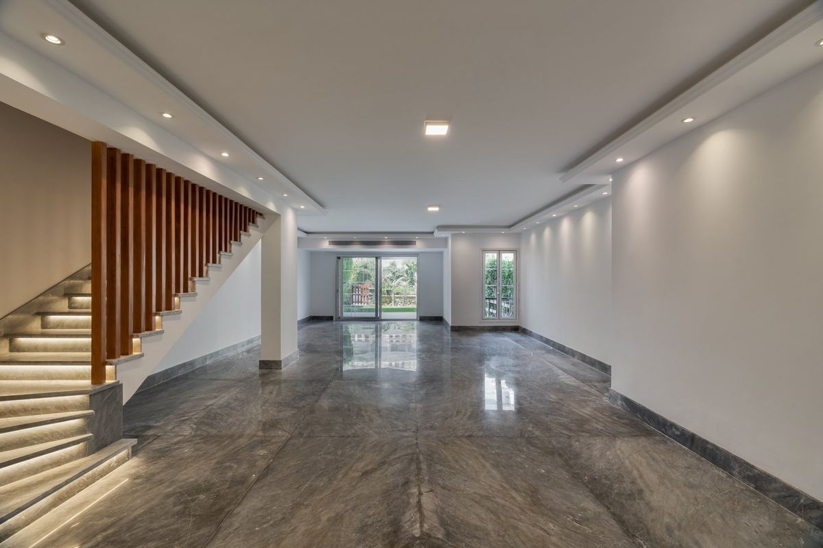 M-Villa ground floor: open living space with a grey marble floor, lit staircase with a timber slat screen and garden doors
