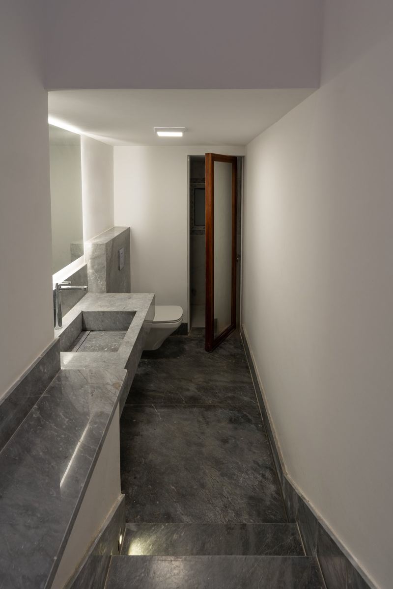 M-Villa bathroom under the stairs with the mirror door open to hidden storage