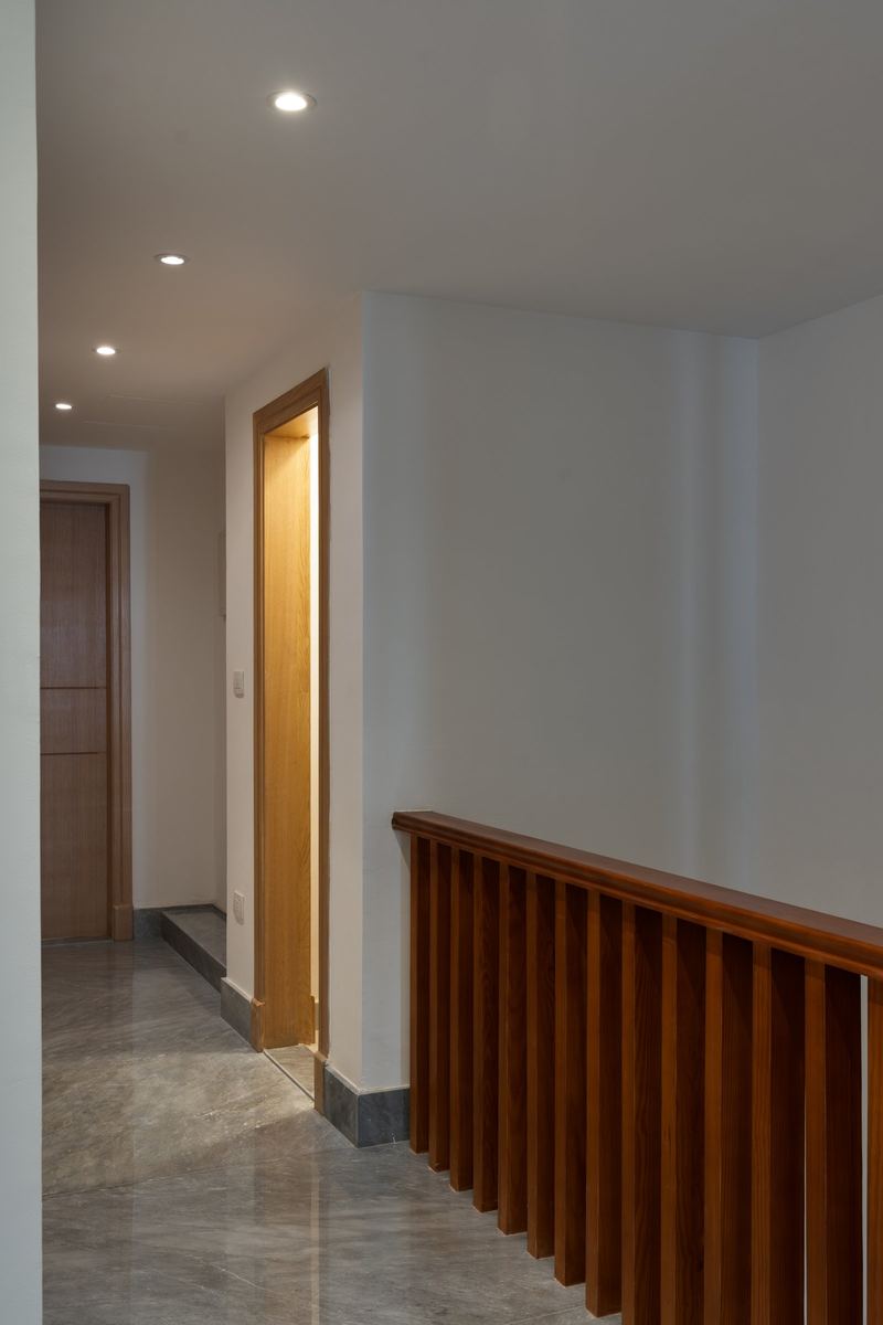 M-Villa upper hallway: marble floor, timber doors and the slatted wooden balustrade