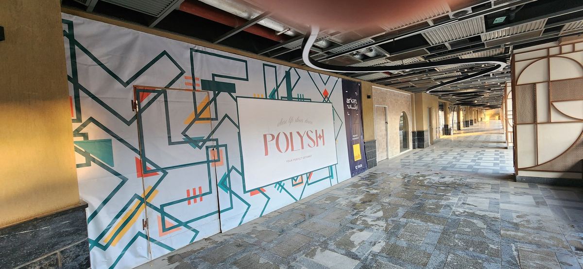 Before: The Polysh shop unit behind a printed hoarding in the Arkan mall corridor