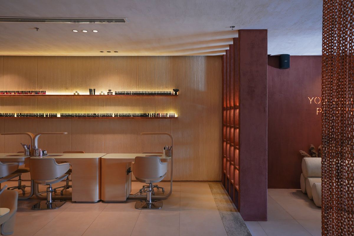 Polysh manicure stations with warm linear lighting and terracotta walls
