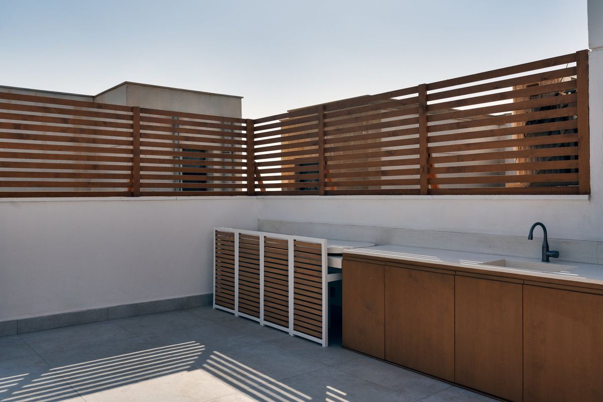 Sodic rooftop outdoor kitchen: timber cabinets and louvred storage, table tucked away