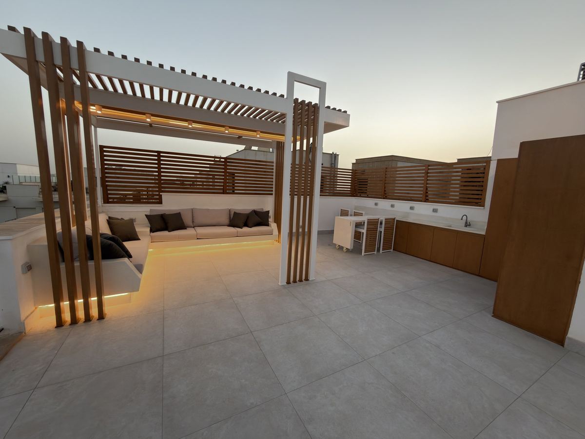 At dusk as delivered: the lit pergola, and the outdoor kitchen along the timber screen